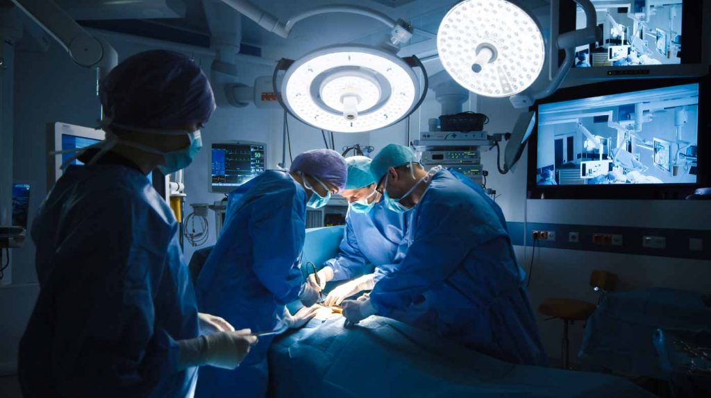 A team of surgeons performing surgery in a modern operating room equipped with advanced medical technology and lighting.